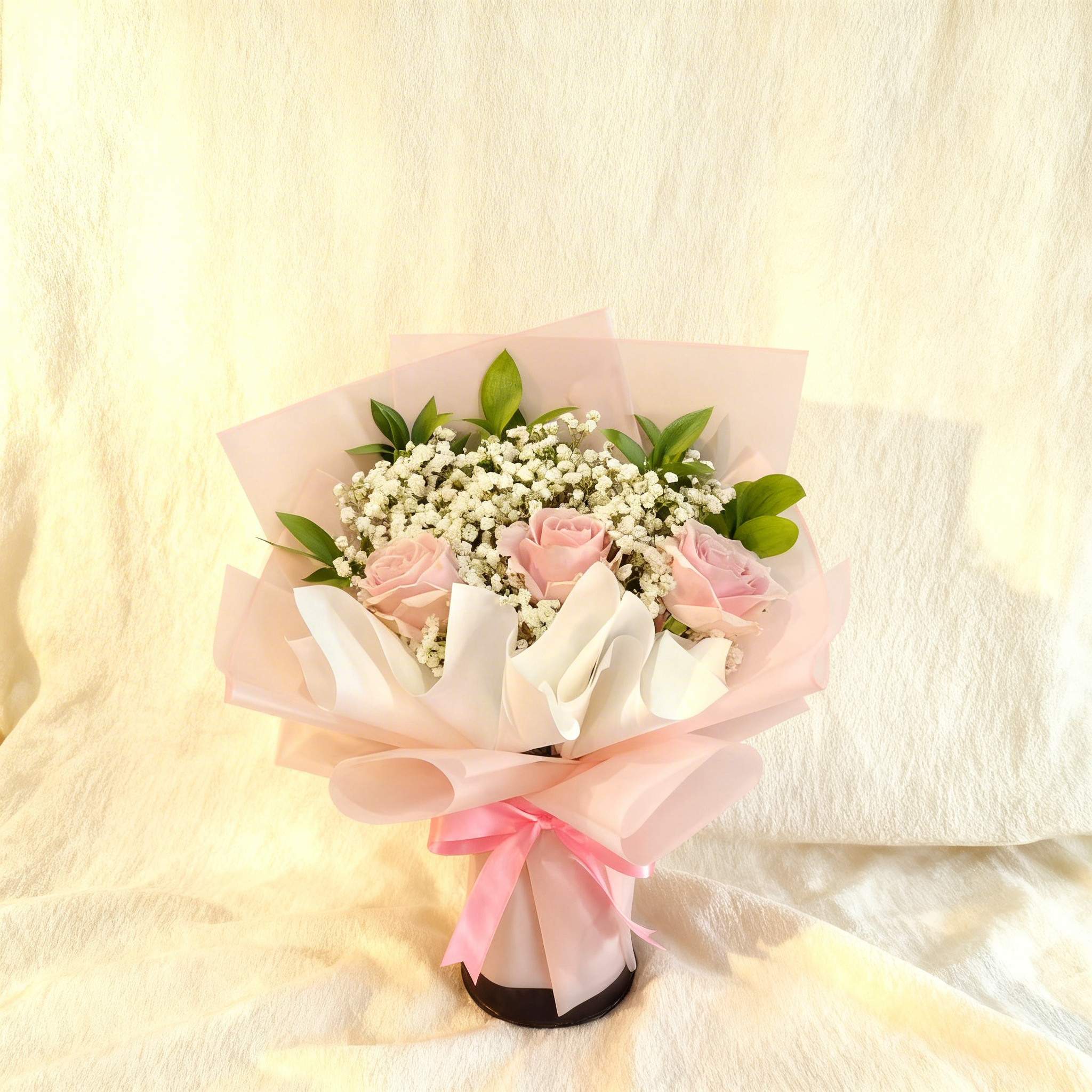 Bouquet of 3 pink roses with fillers, beautifully wrapped in paper and tied with ribbons.
